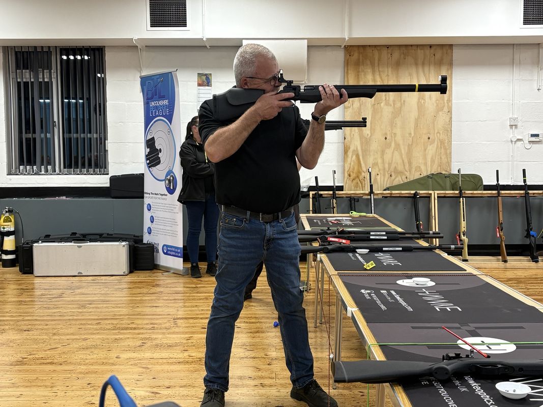 A competitor standing at a shooting table with an air rifle